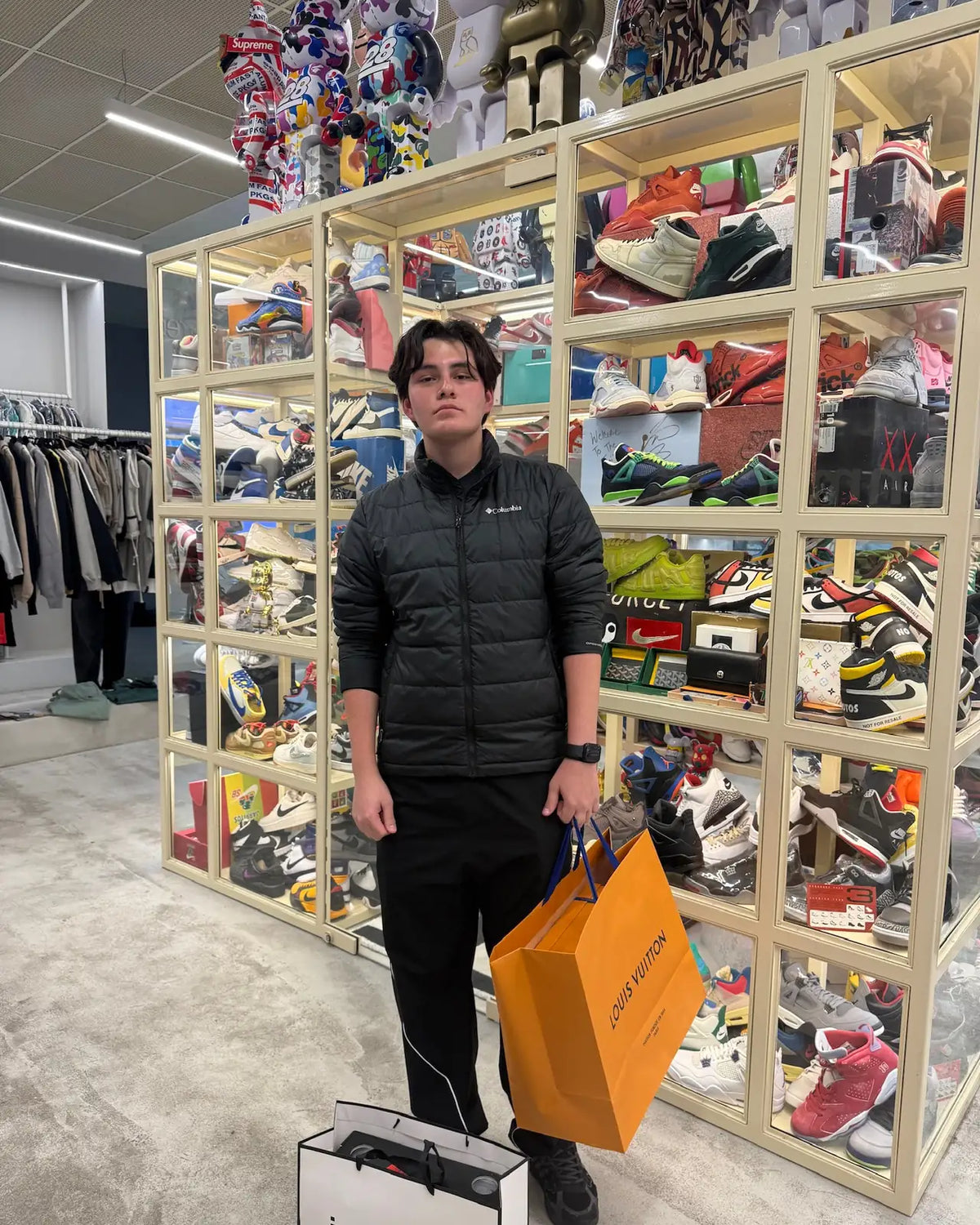 Customer with a Louis Vuitton bag beside the sneaker display case at Immense Galerie