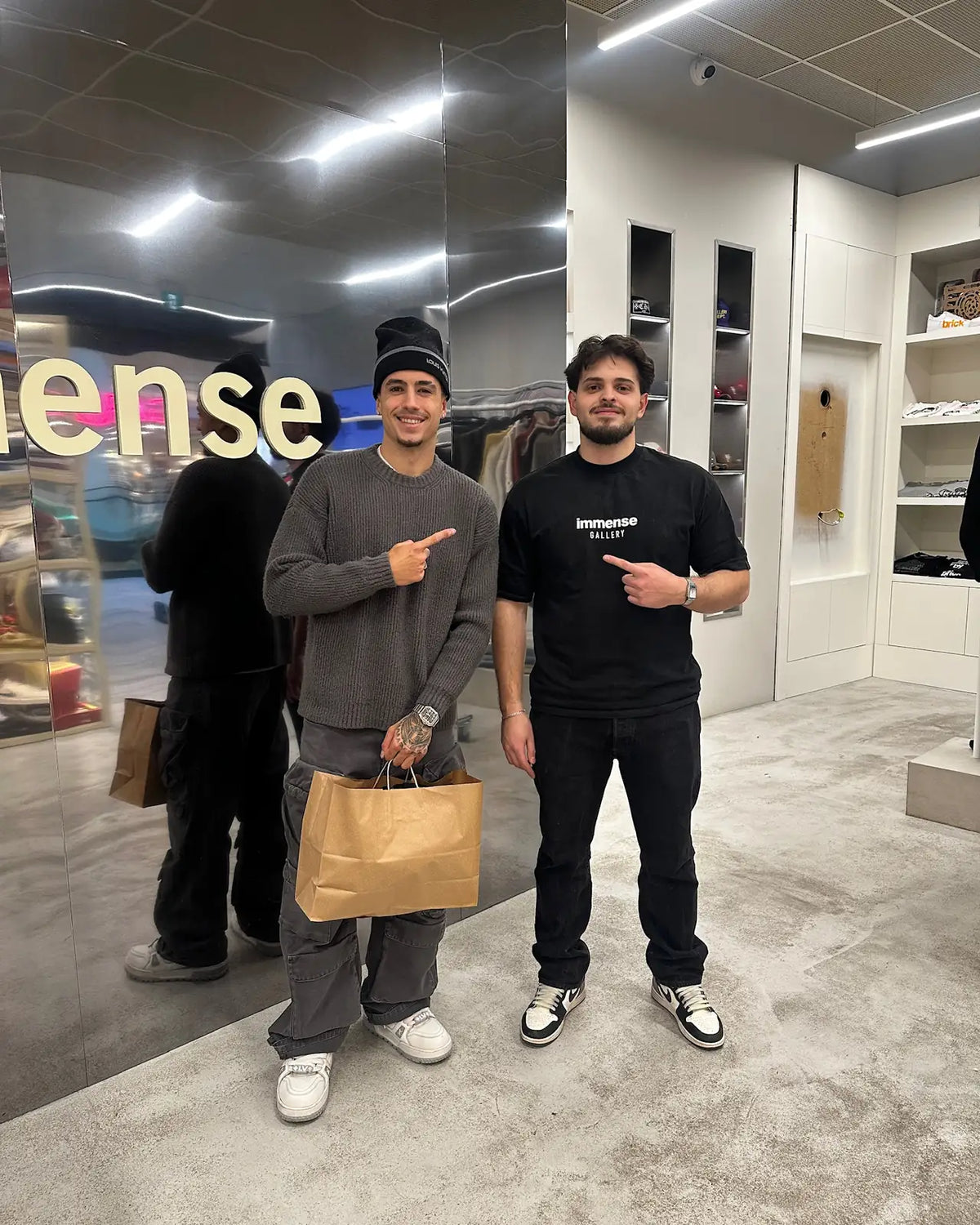Two customers in front of the mirrored Immense logo wall at the Royalmount store